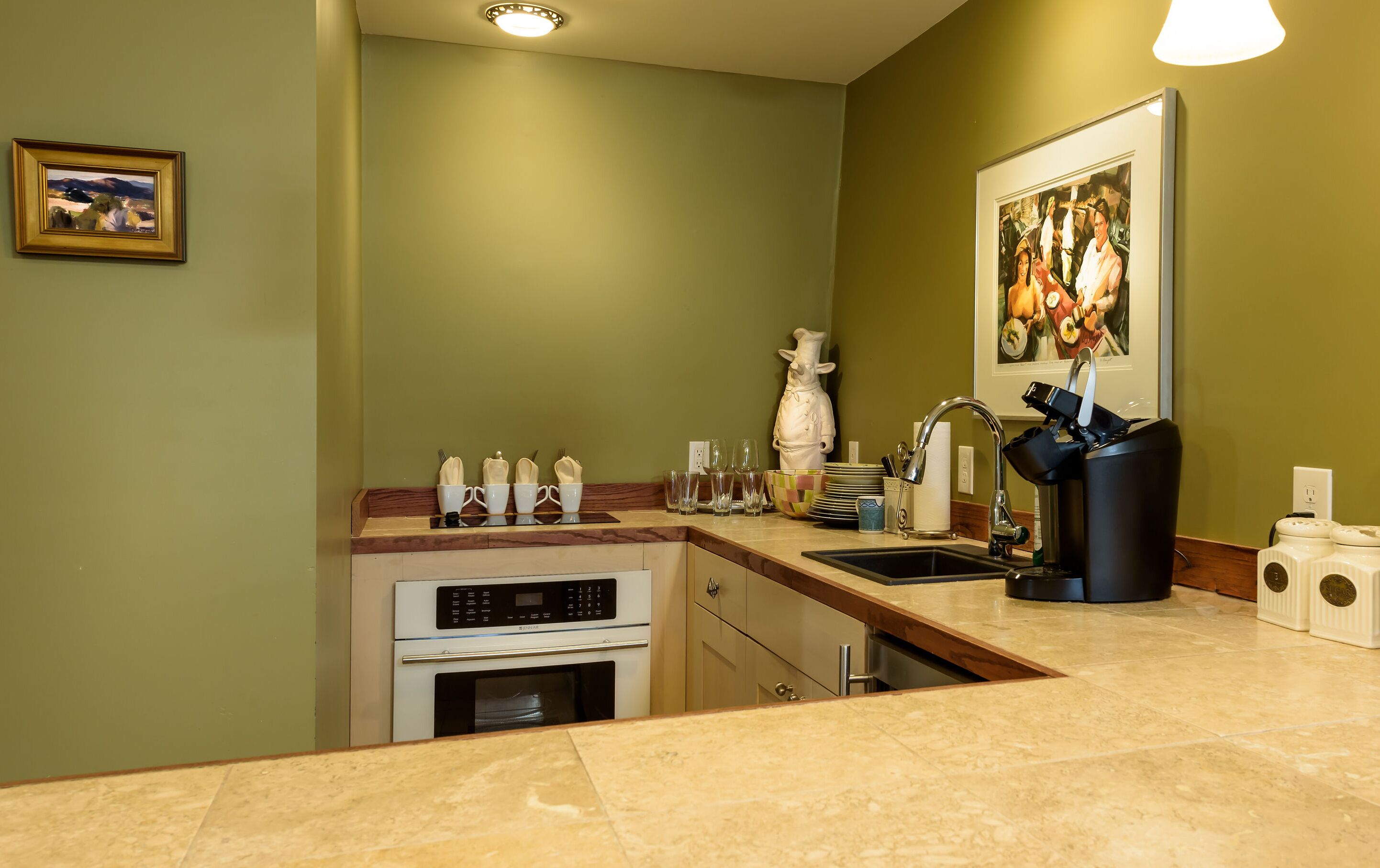 A modern kitchen with a built-in oven, a sink, and a countertop with various kitchen items.