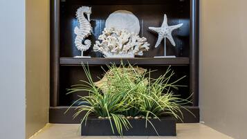 A bathroom with a shelf containing decorative items like starfish and shells, and towels with pockets.
