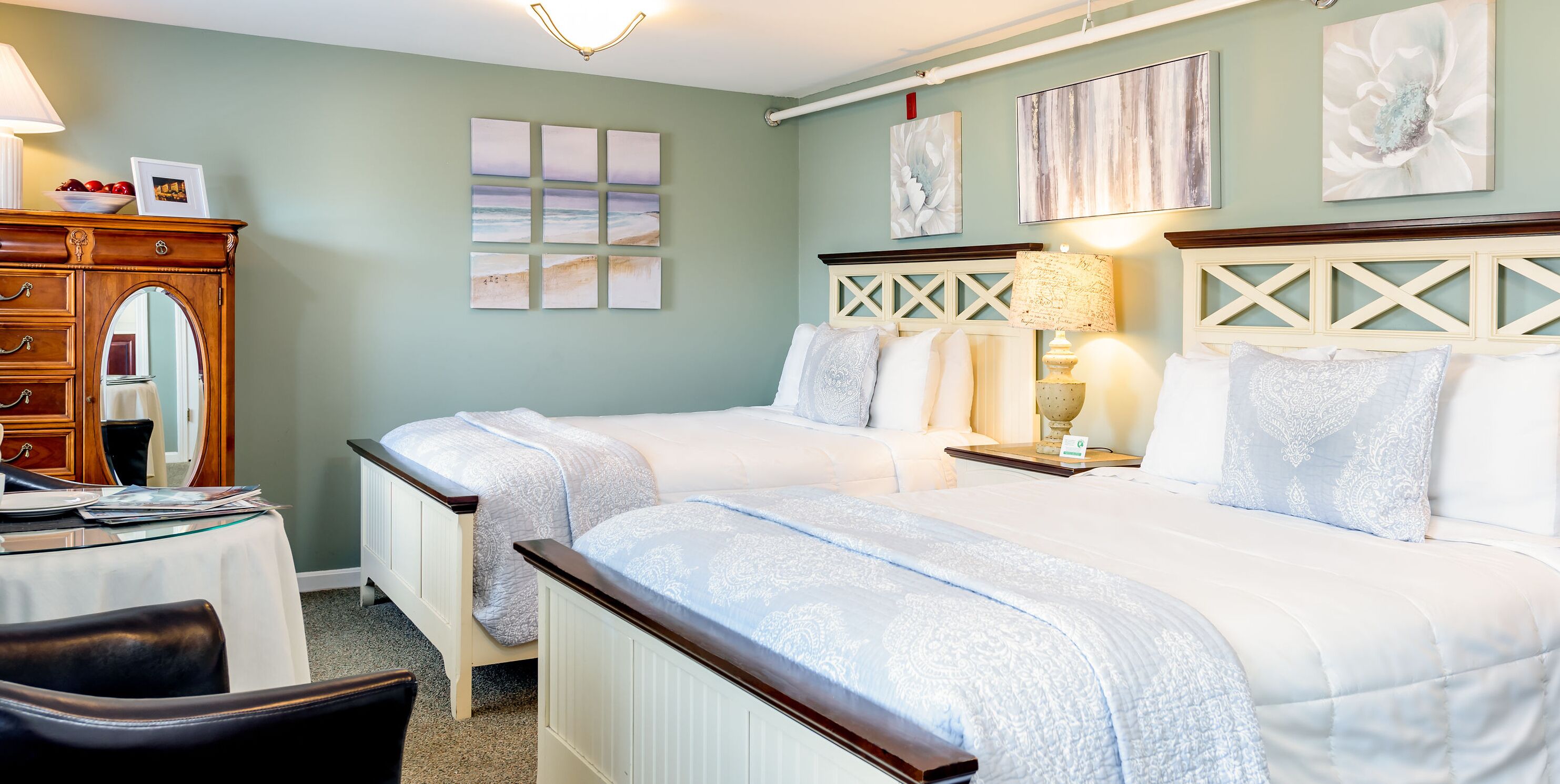A bedroom with two beds, a dresser, a desk, and a chair.
