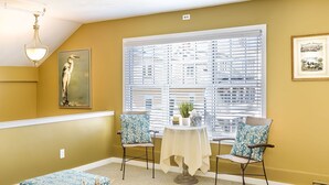 A room with yellow walls, a staircase, a dining area with chairs and a table, and a television on the wall. - Bouchard Inn (Newport)