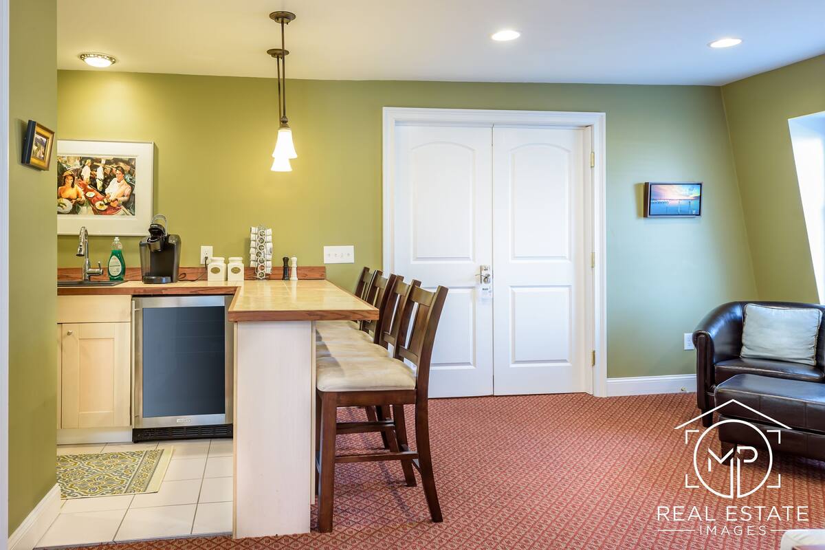 A kitchen with a wooden island, a dining area with chairs, a dishwasher, and a refrigerator.