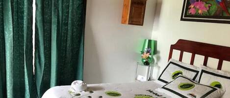 A bed with a wooden headboard, a green curtain, and a framed picture on the wall.