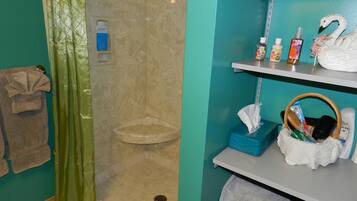 Un baño con ducha, toallero y repisas con artículos de aseo.