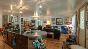 A spacious living area with a large island, wooden flooring, and a dining area with chairs and a table. - A Garden Stroll B&B (Stratford)