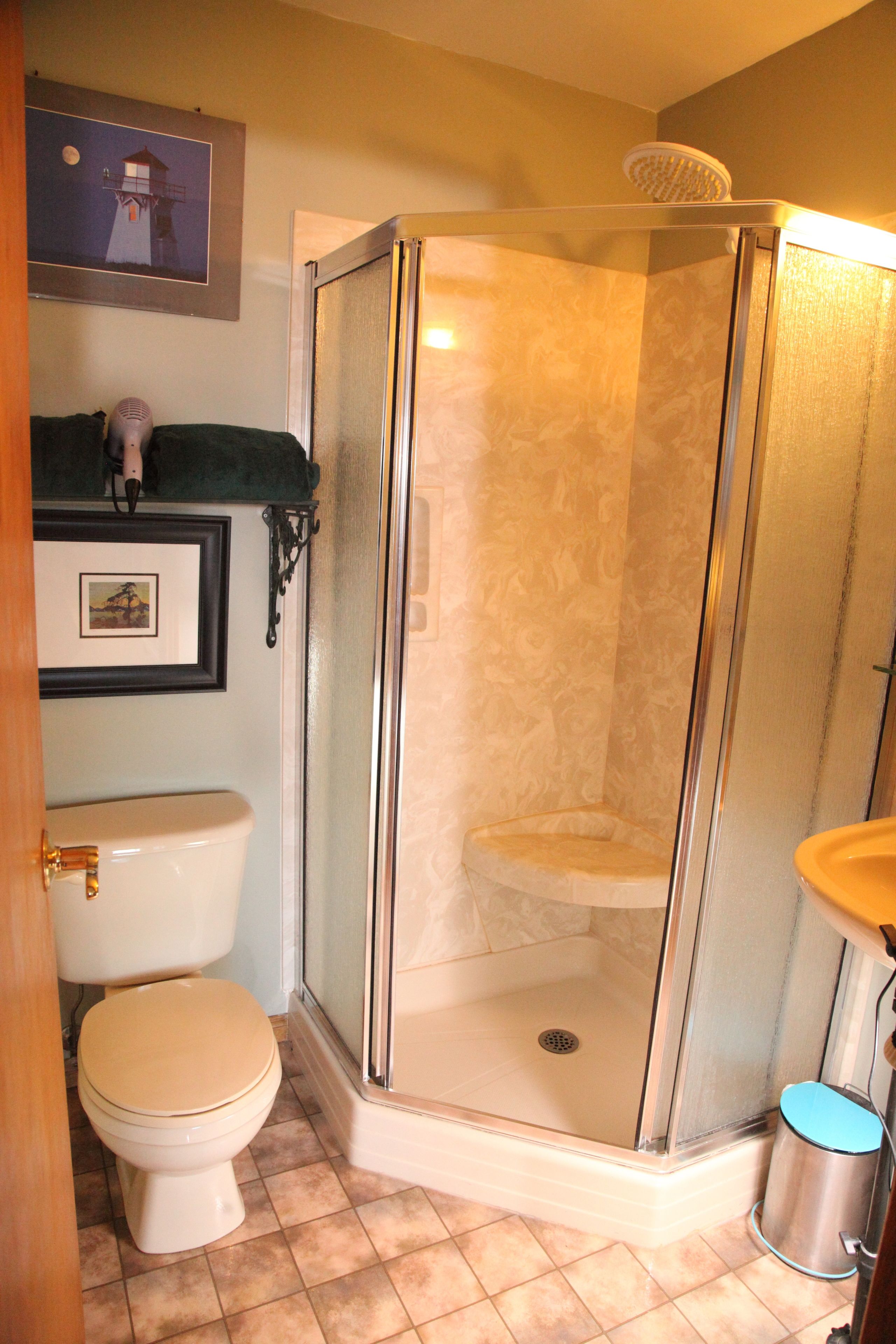 Un baño con inodoro, cabina de ducha y lavamanos.
