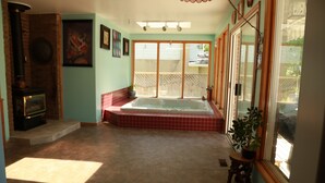 A spacious room with a large window, a fireplace, and a bathtub. - A Garden Stroll B&B (Stratford)