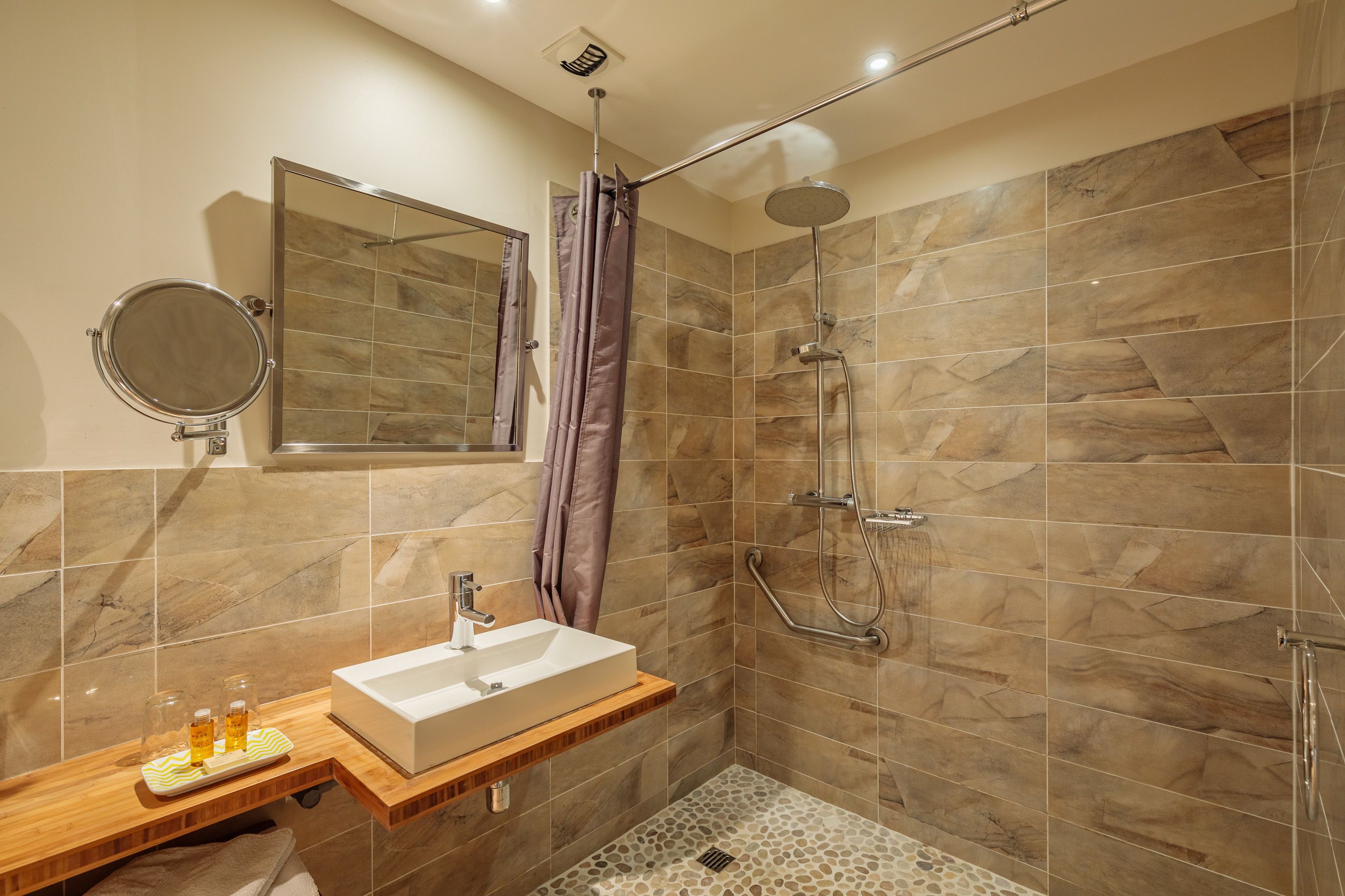A modern bathroom with a shower, a sink, and a mirror.