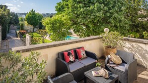 Terraza en la azotea con mobiliario de mimbre, piscina y abundante vegetación.