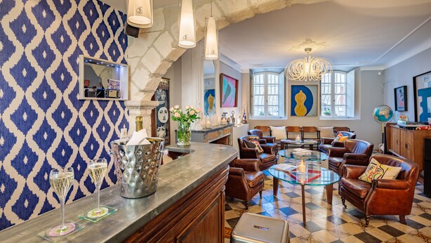 Zona de bar con pared decorada, sofás de cuero, una mesa de vidrio y una araña.