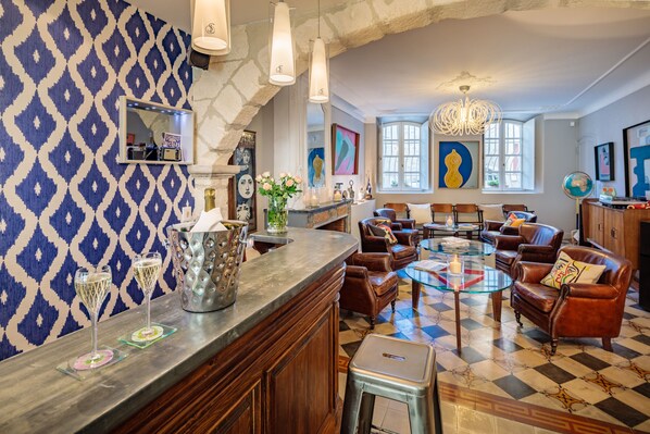 Un espace bar agrémenté d’un mur à motifs, de canapés en cuir, d’une table en verre et d’un lustre.