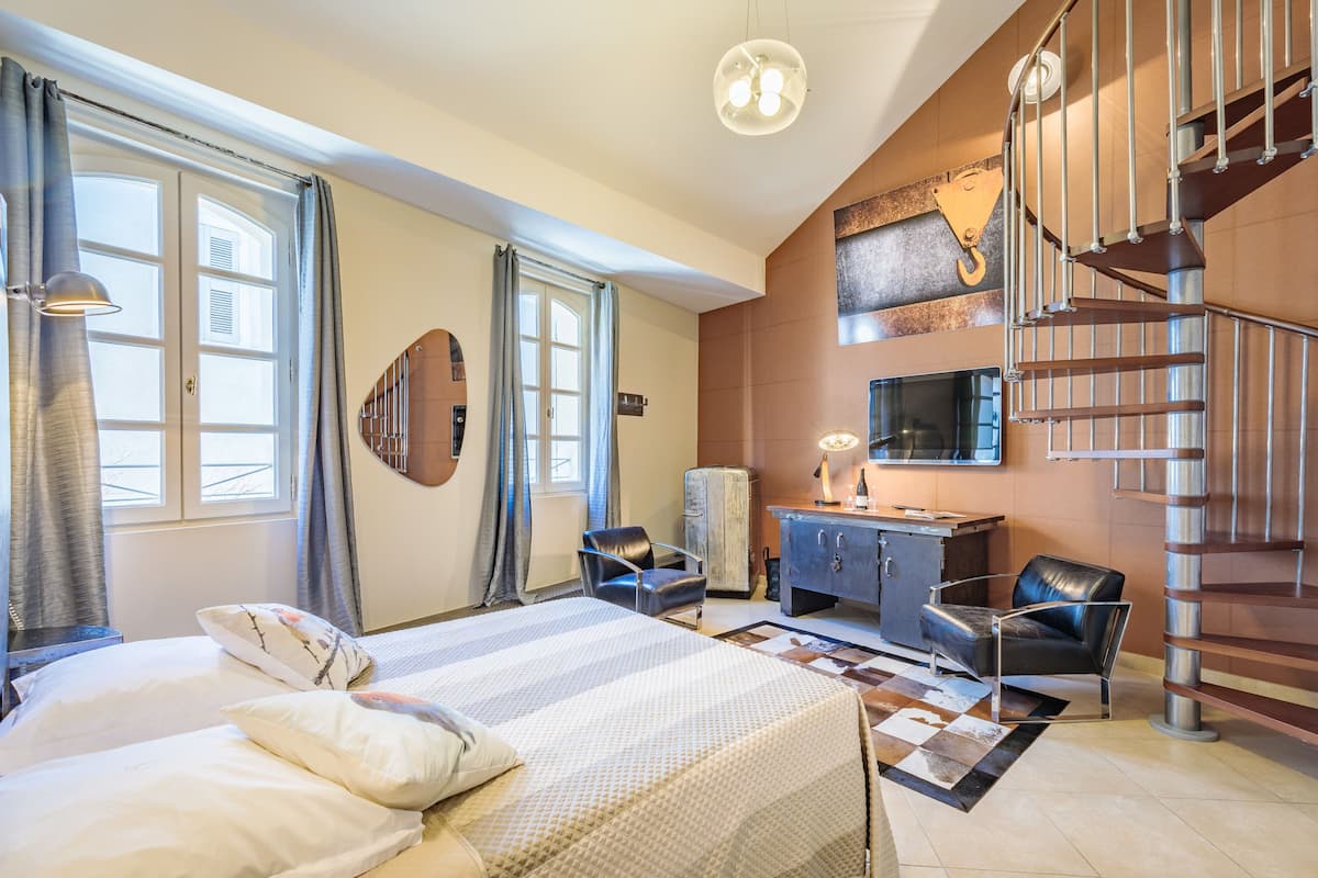 Une chambre à coucher comprenant un lit, deux chaises, un bureau et un escalier en colimaçon.