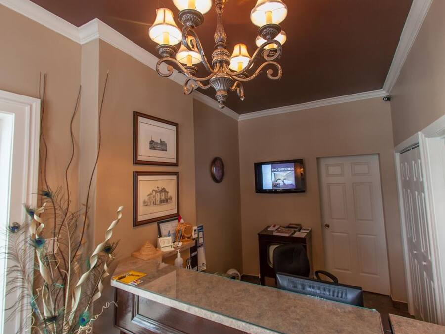 A kitchen with a dark wooden cabinet, a glass countertop, a chandelier, and a television on the wall.