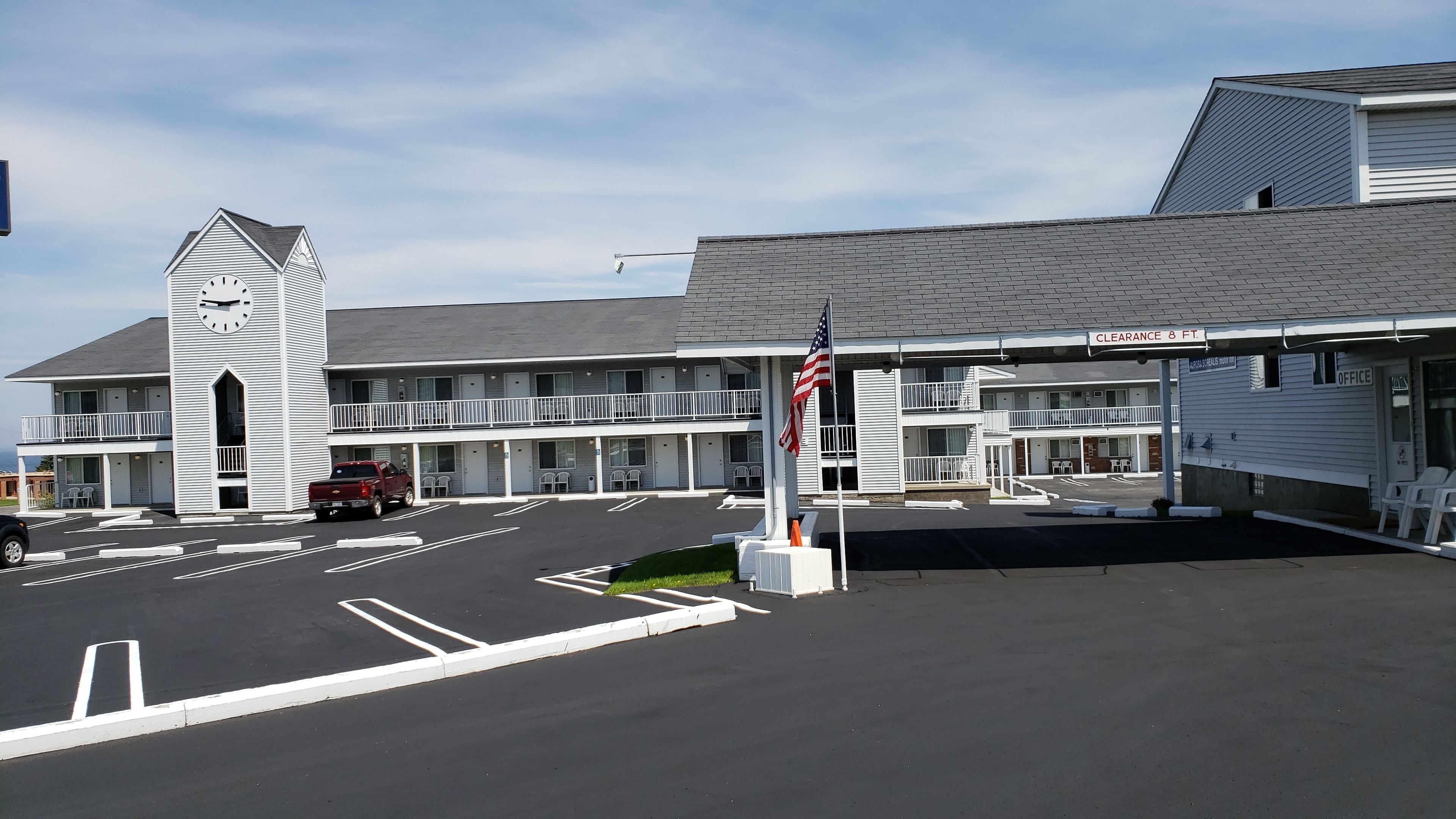 A motel with a two-story structure, a parking lot, and an American flag.