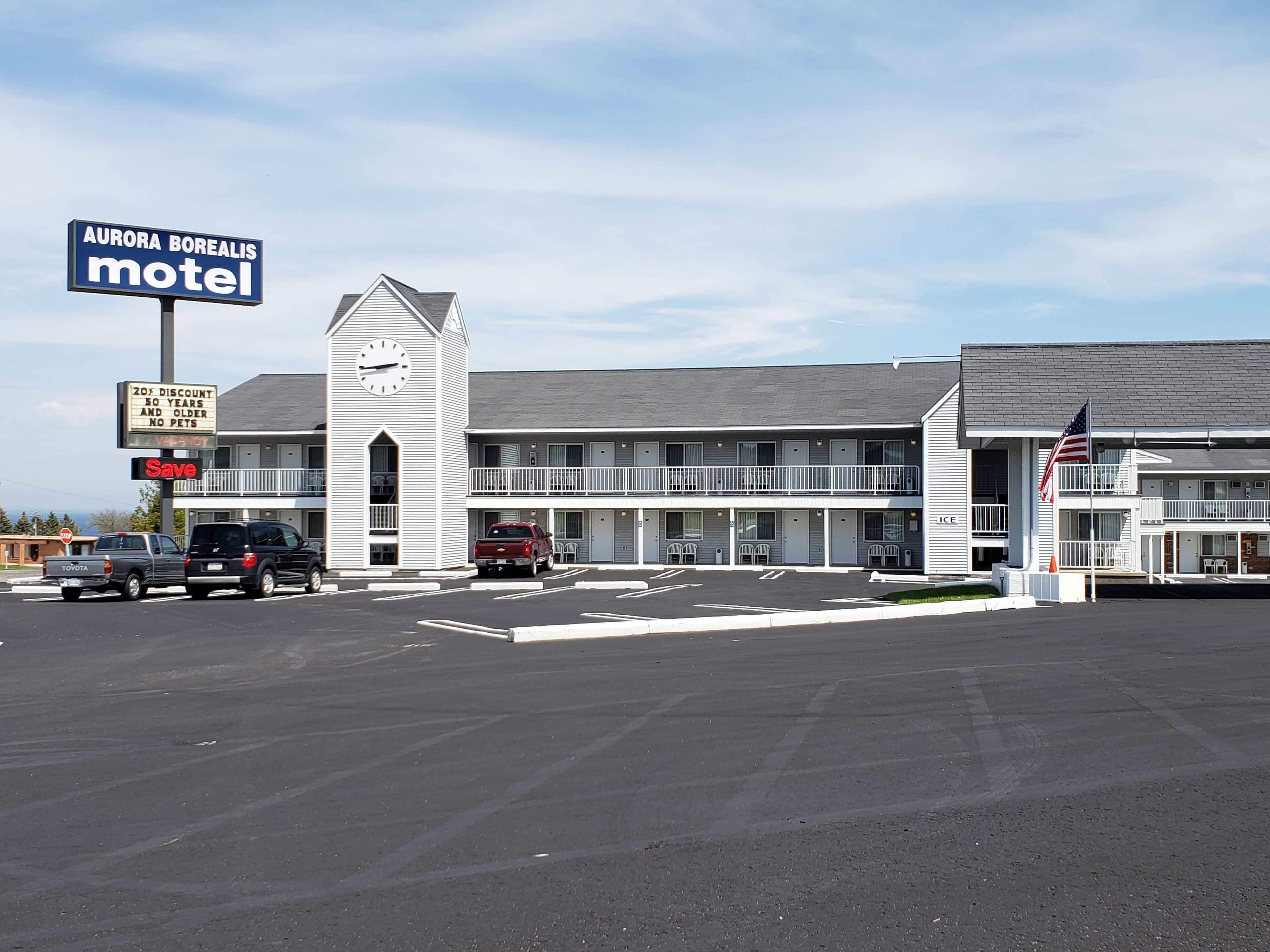 Un motel con un letrero llamativo, una torre de reloj y una estructura de dos pisos con balcón.