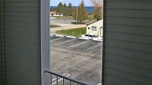 A view from a balcony with a metal railing, overlooking a parking lot and buildings. - Aurora Borealis Motel (St Ignace)