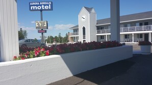 A motel with a signboard, a stop sign, and a building with a balcony. - Aurora Borealis Motel (St Ignace)