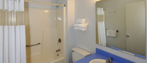 A bathroom with a bathtub, toilet, sink, and a mirror.