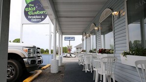 A roadside diner named "The Wild Blueberry Breakfast & Bakery" with outdoor seating and a parked truck. - Aurora Borealis Motel (St Ignace)