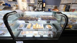 A bakery display case with various baked goods like muffins, pastries, and bread. - Aurora Borealis Motel (St Ignace)