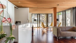 A modern interior with a wooden ceiling, a reception desk, a sofa, and a chair.
