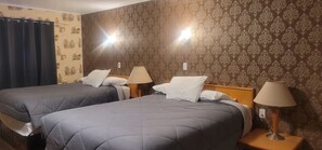 A hotel room with two beds, each with a pillow and a lamp on a bedside table.