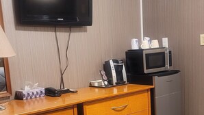 A hotel room with a wooden dresser, a flat-screen TV, a microwave, a mini-fridge, and a coffee maker. - Neepawa motel (Neepawa)