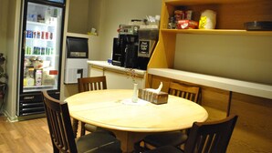 A dining area with a round table, chairs, a refrigerator stocked with beverages, a coffee machine, and a shelf with condiments. - Neepawa motel (Neepawa)