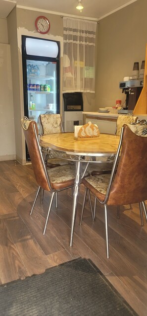 A dining area with a round table, four chairs, a refrigerator, and a clock on the wall. - Neepawa motel (Neepawa)