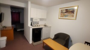 A compact hotel room with a kitchenette, a single bed, a small table, and a TV. - Neepawa motel (Neepawa)