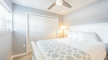 A bedroom with a bed, a ceiling fan, a nightstand, and a window with blinds.