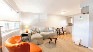 A compact living space with a sofa, a small table, a chair, a lamp, and a refrigerator.