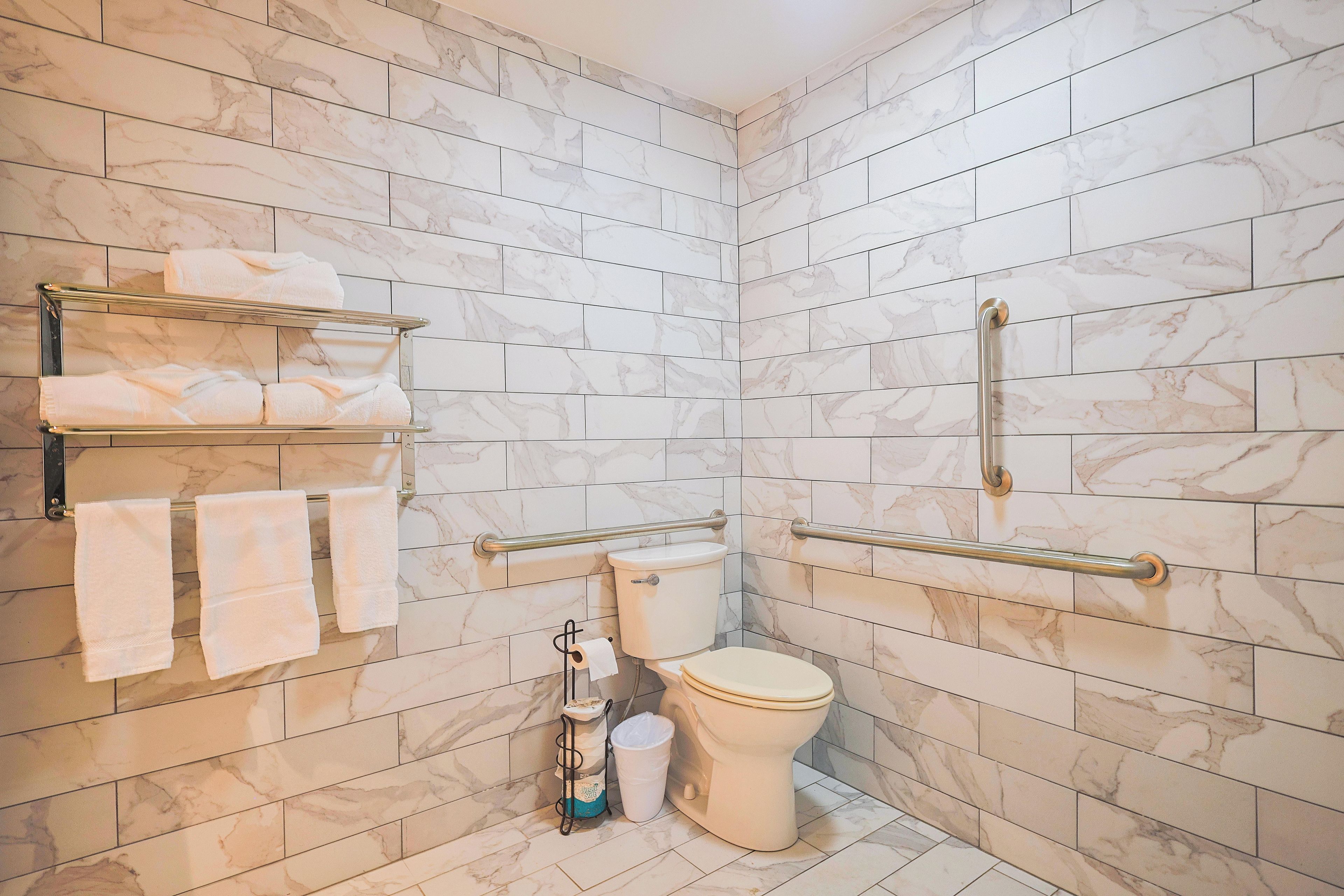 A bathroom with marble tiles, a toilet, a hand dryer, and a towel rack.