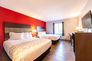 Una habitación de hotel con dos camas, televisión y escritorio.
