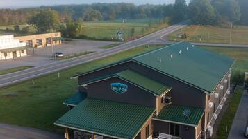 A hotel with a green roof, a parking lot, and a road in the background.