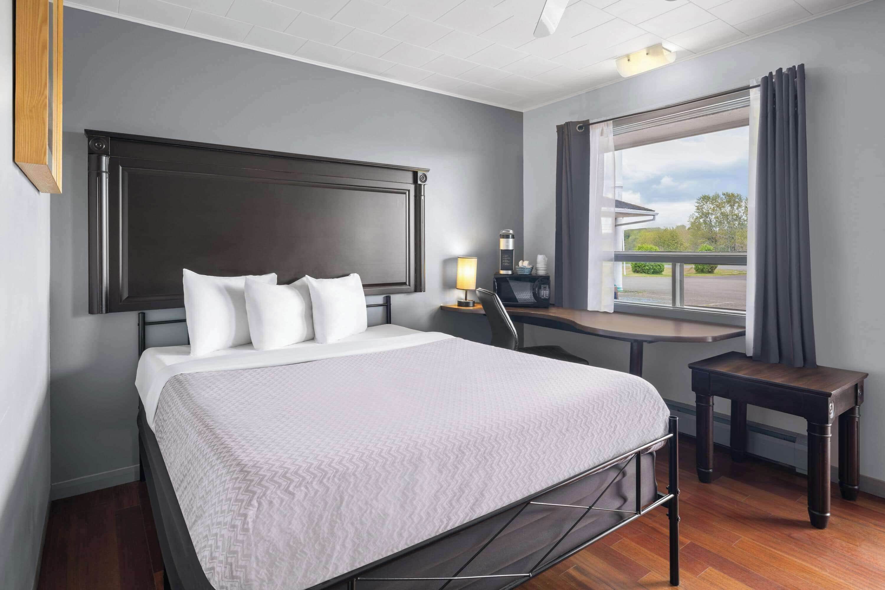 Una habitación de hotel con una cama grande, un escritorio y un ventanal con cortinas.