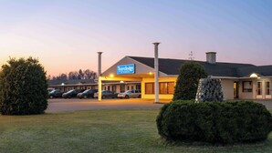 A Travelodge hotel with a parking lot, a signboard, and a well-maintained lawn. - Travelodge by Wyndham Grand Falls (St. Andre)