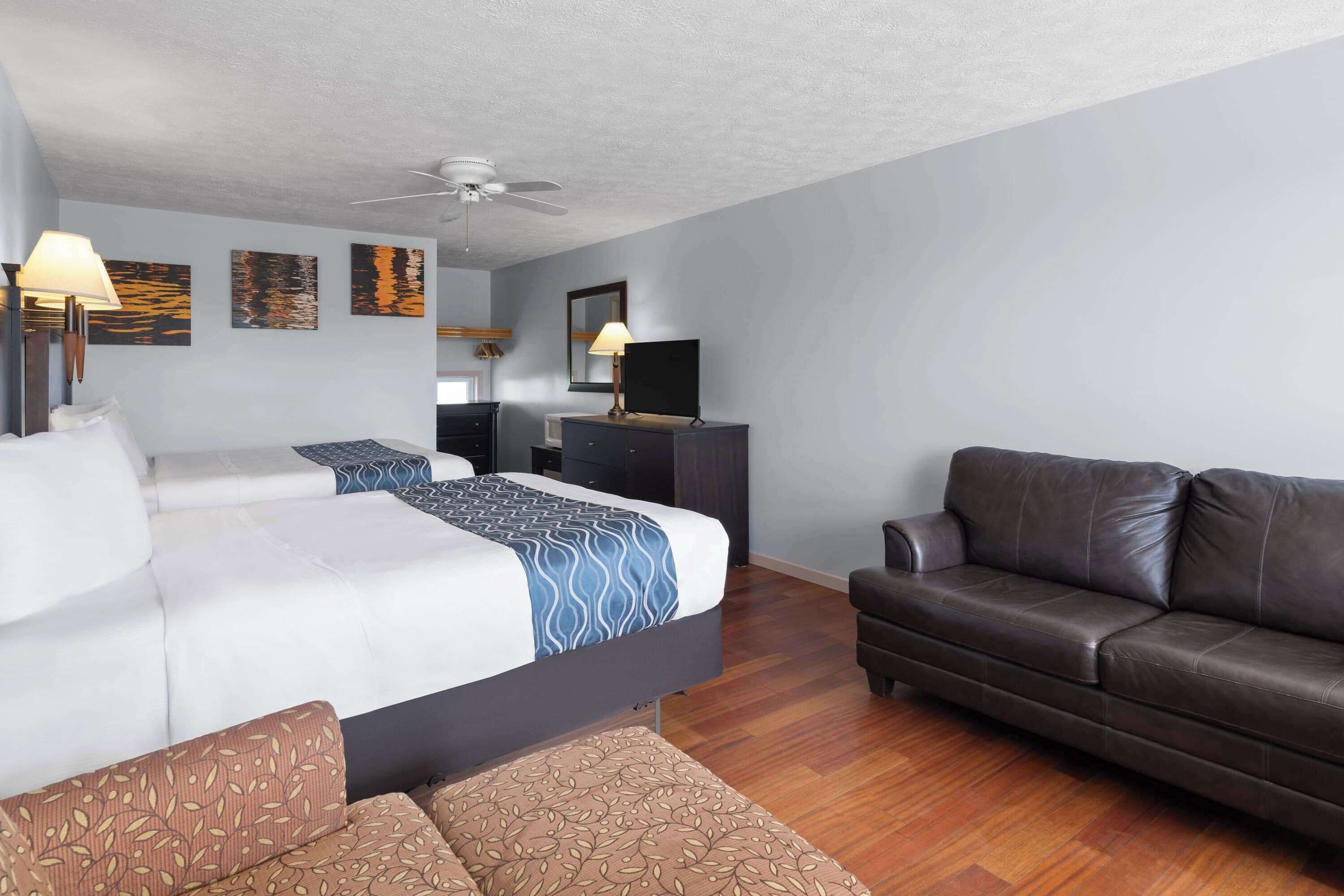 Una habitación de hotel con cama, sofá, escritorio y ventilador de techo.