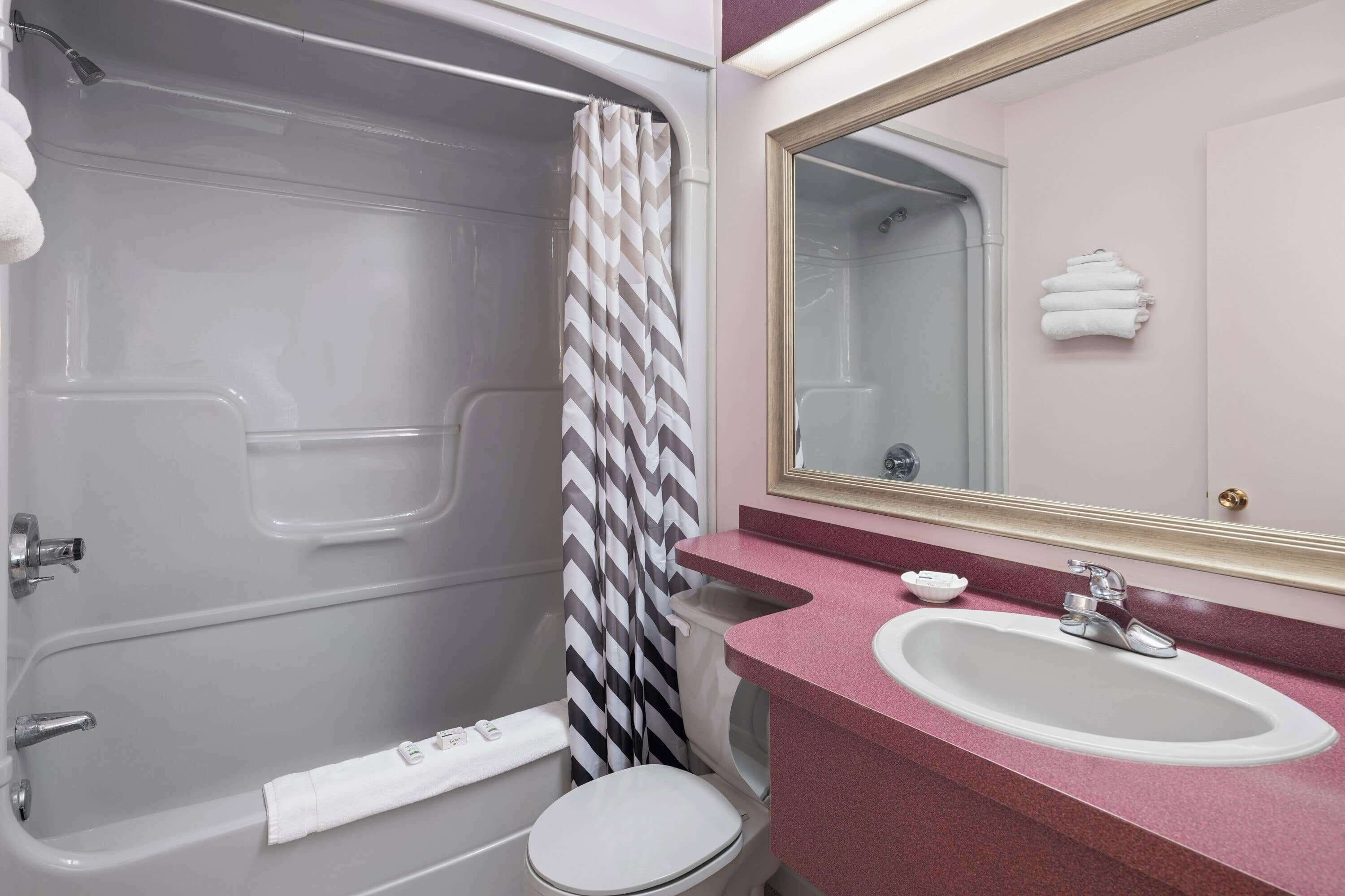 A bathroom with a bathtub, toilet, sink, and a mirror.