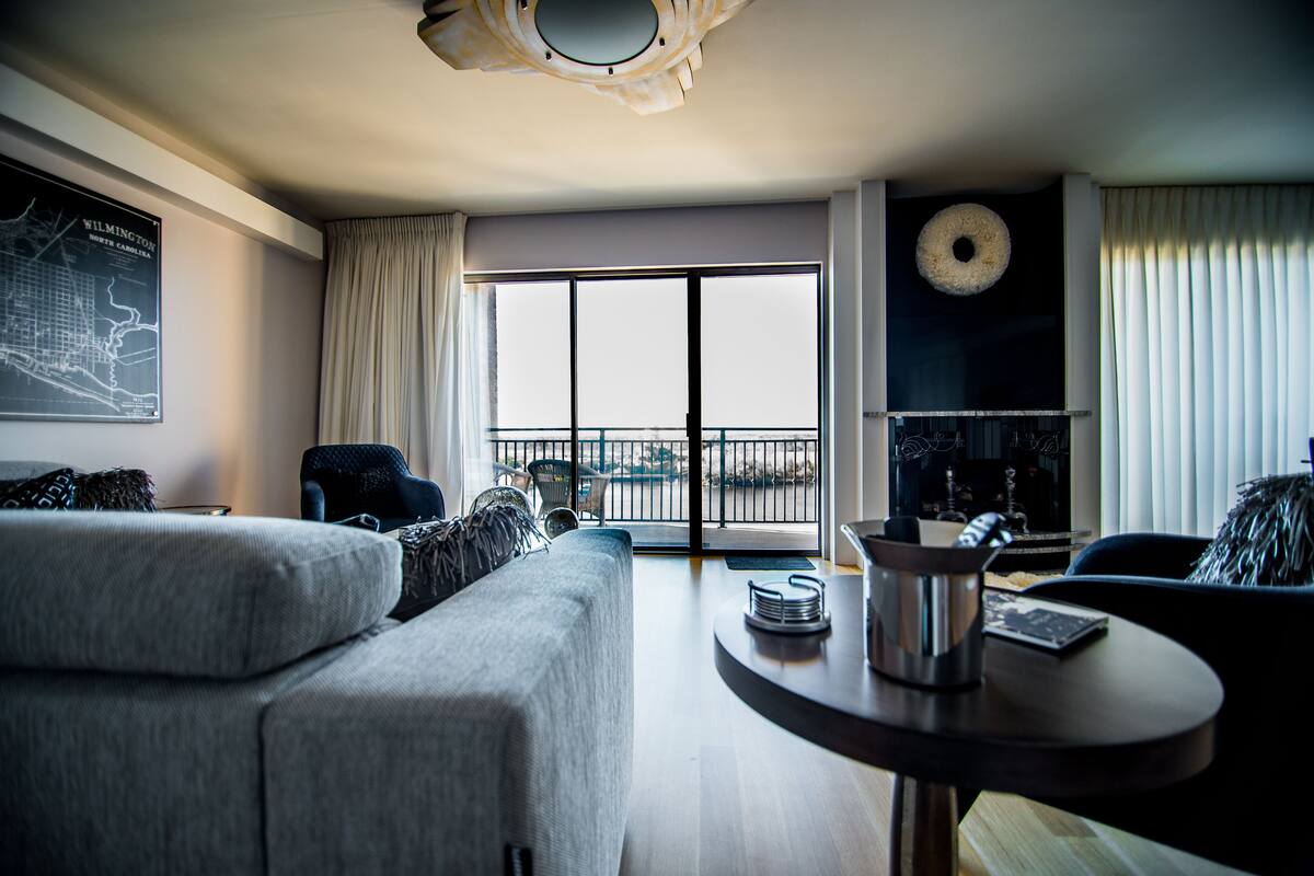 A modern living room with a sofa, a round table, and a large window with a view.