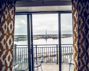 A balcony with metal chairs, a view of a river, and a distant ship. - Water Street Retreats (Wilmington)
