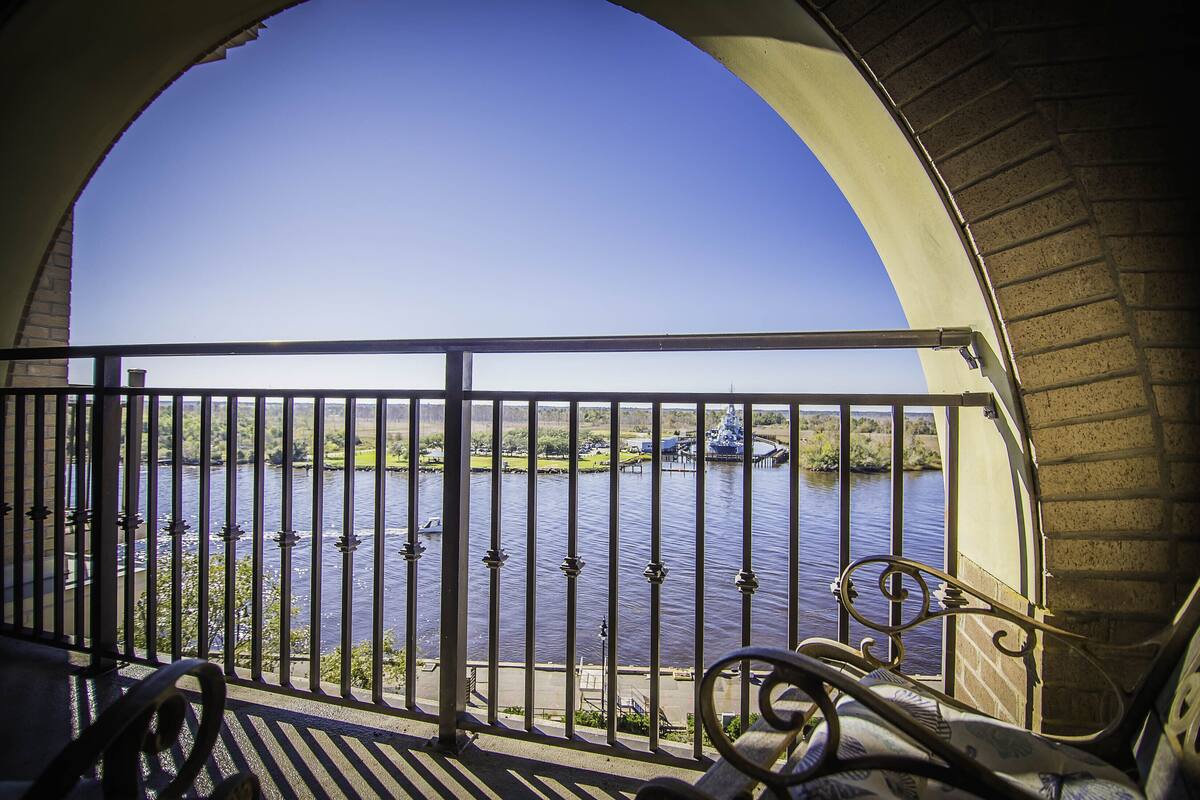 A balcony with a metal railing overlooking a river.