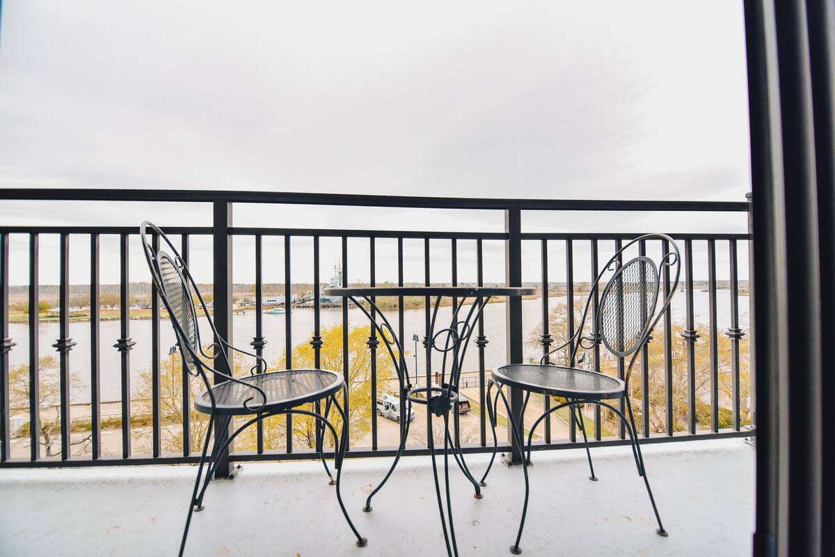 A balcony with a metal railing, two chairs, and a small table.