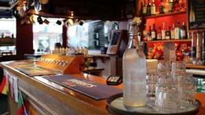 A bar area with a selection of liquor bottles, a large bottle of water, and multiple glasses on a tray. - Law Courts Hotel (Dunedin)