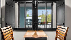 A room with a large window, a wooden table, two wooden chairs, and a black metal structure in the center. - Country Town N Suites (Gatlinburg)