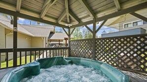 A hot tub under a wooden deck with a lattice fence and a house in the background. - Country Town N Suites (Gatlinburg)