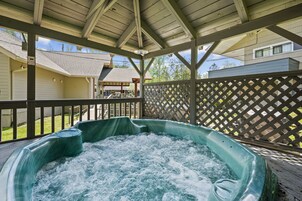 A hot tub under a wooden deck with a lattice fence and a house in the background.