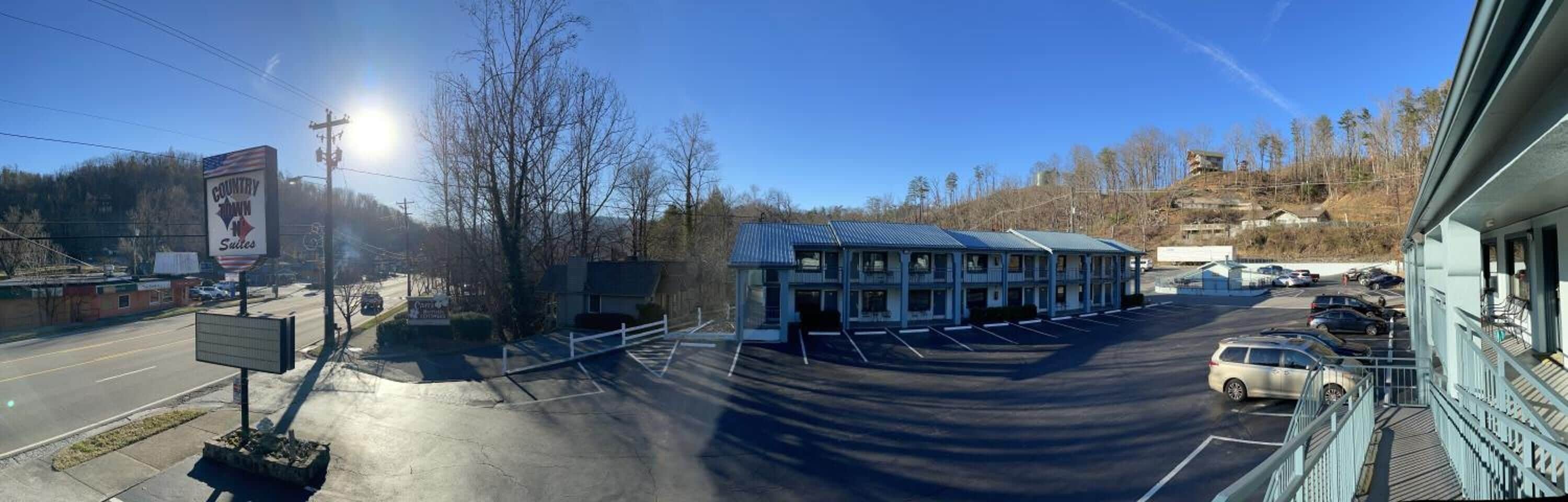 A motel with a parking lot and a building with a blue roof.