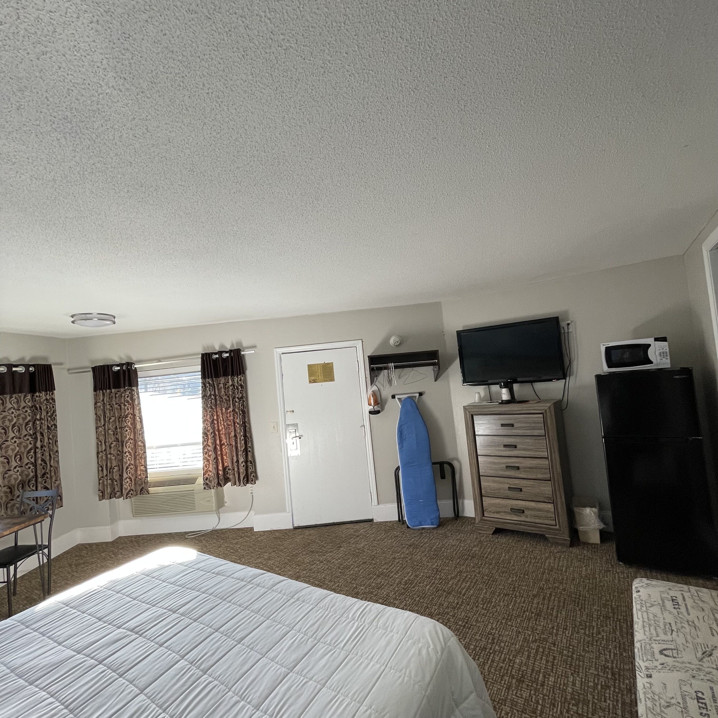 Une chambre d’hôtel avec un lit, une télévision, une commode et une porte.