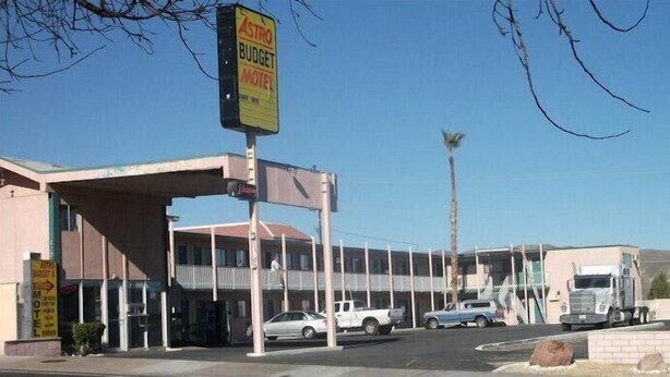 Un motel avec une station-service, plusieurs places de stationnement et un grand camion garé à l’extérieur.