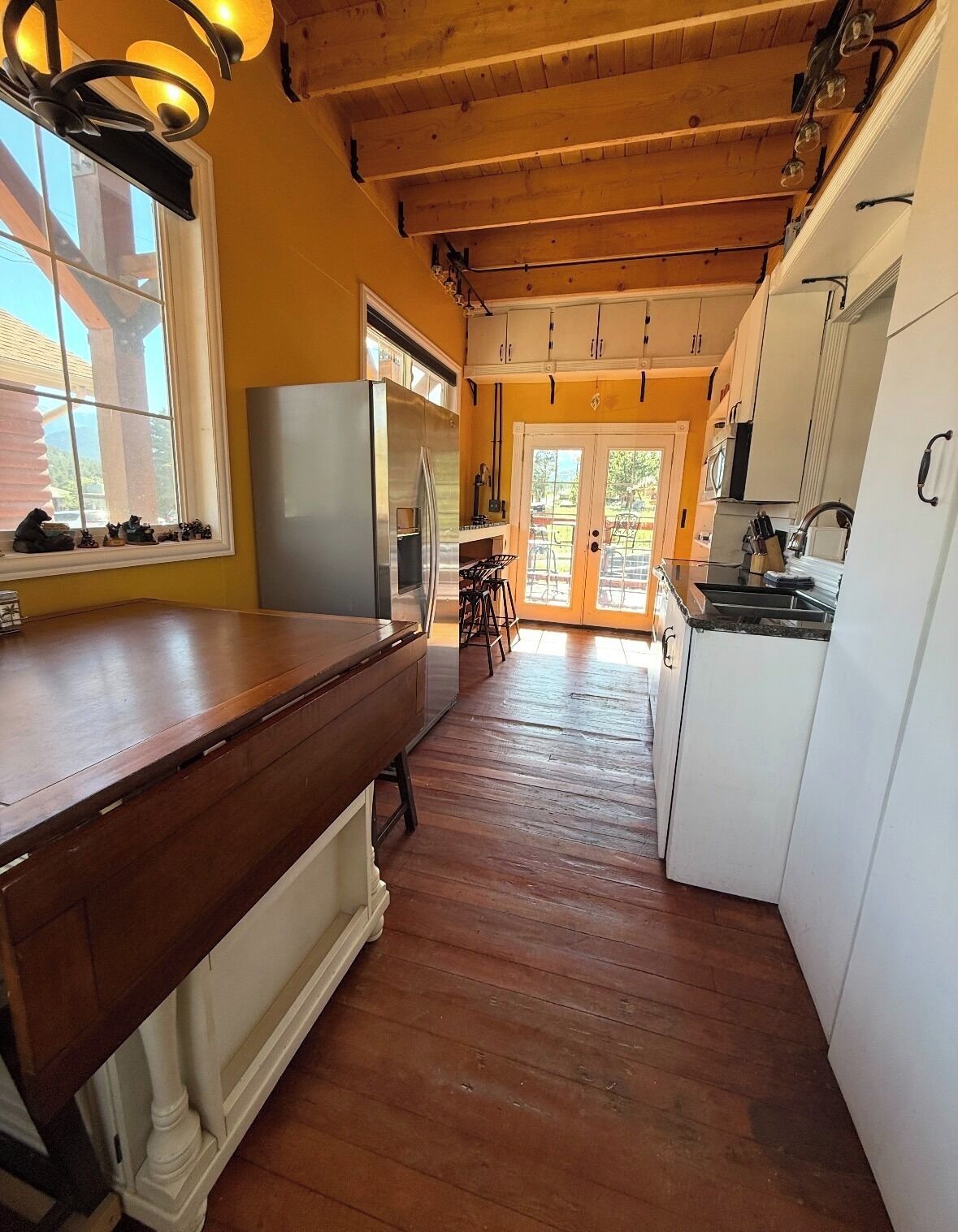 Eine Küche mit Holzboden, weißen Schränken und einem großen Fenster.